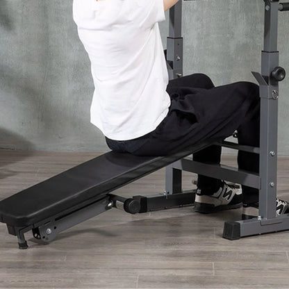 Person using a black adjustable weight bench in a gym setting.